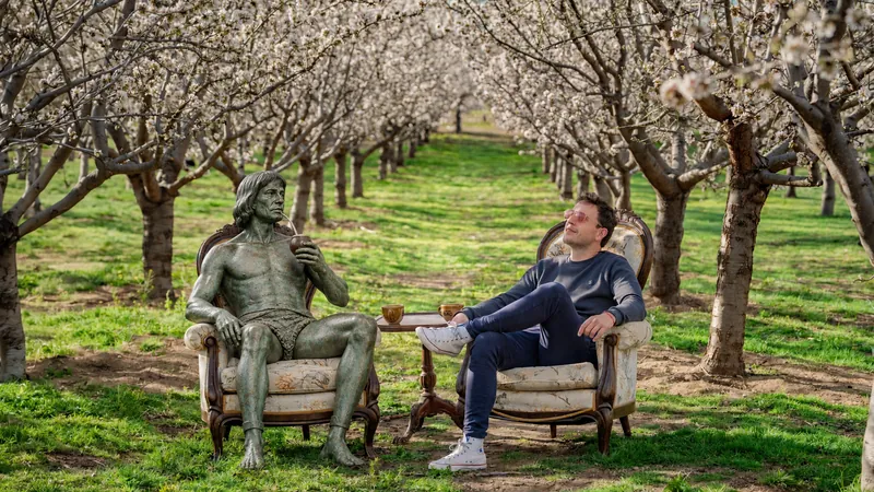 Escena creativa de Jema IA Lab: una figura de bronce y un hombre sentados entre árboles en flor